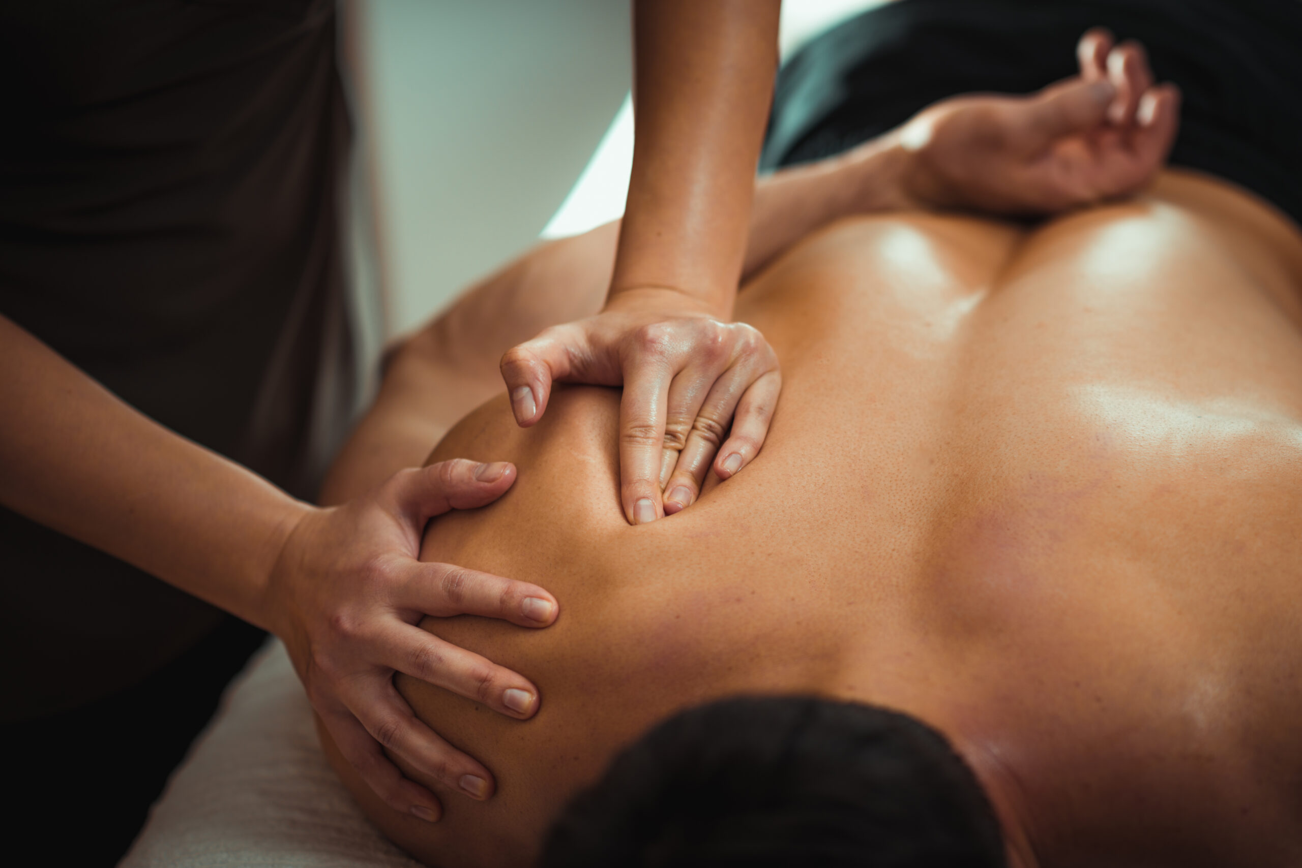 Physiotherapist massaging male patient with injured shoulder blade muscle sports